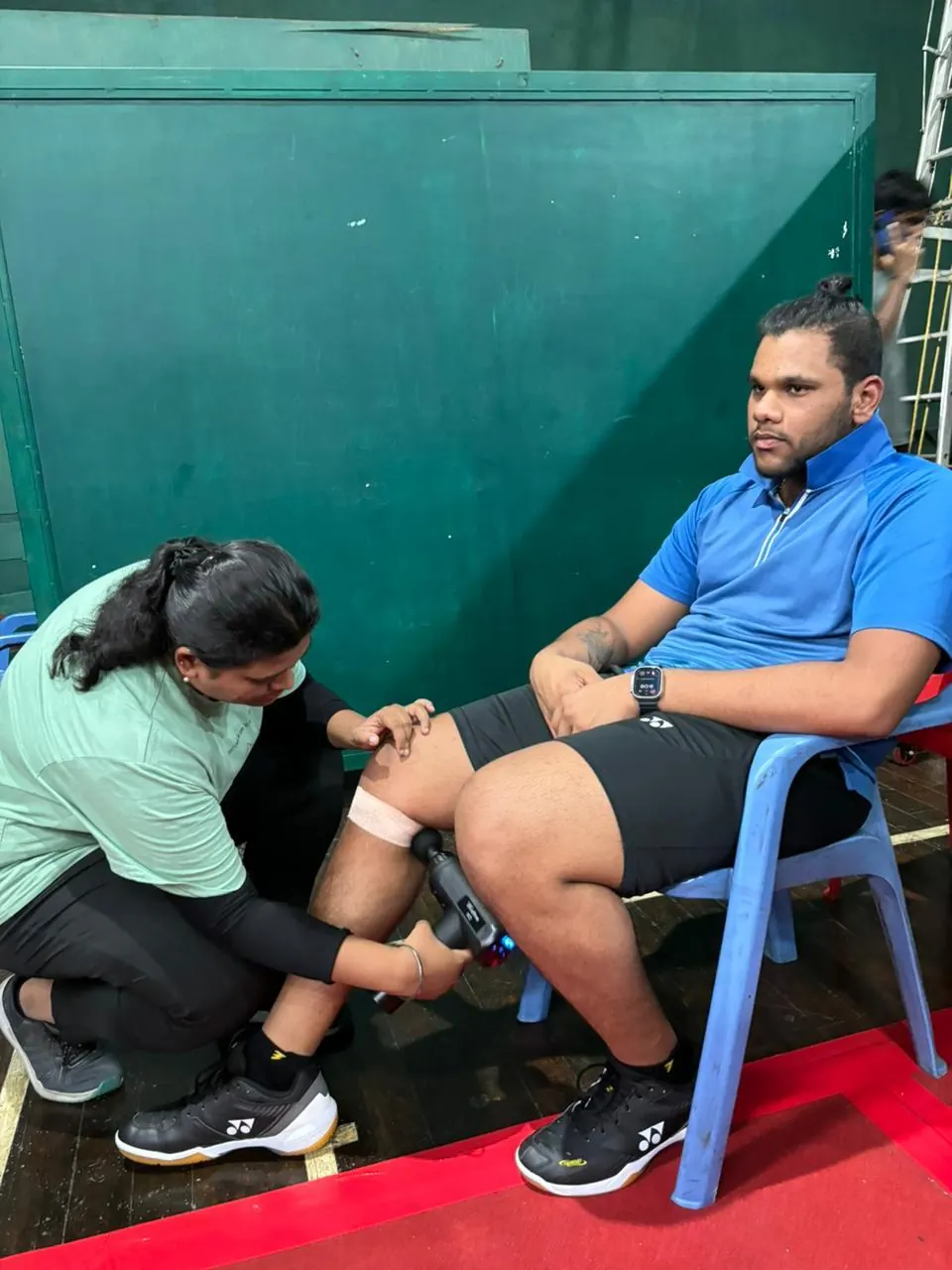 Taping an athlete's knee at a sports event