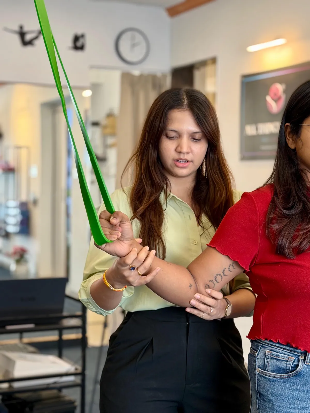 Physiotherapist guiding a patient through a resistance band shoulder exercise at All Things Physio