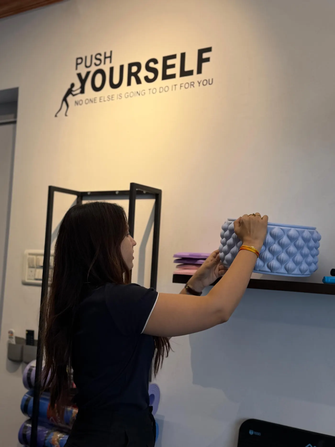 Physiotherapist setting up rehab equipment under the Push Yourself wall